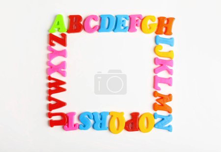 Téléchargez les photos : Frame of colorful magnetic letters on white background, flat lay with space for text. Alphabetic order - en image libre de droit