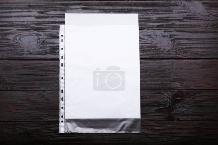 Photo for Punched pocket with paper sheet on brown wooden table, top view. Space for text - Royalty Free Image