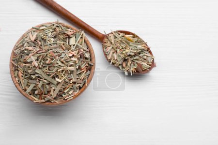 Téléchargez les photos : Bowl and spoon with aromatic dried lemongrass on white wooden table, flat lay. Space for text - en image libre de droit