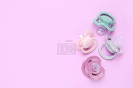 Photo for Flat lay composition with baby pacifiers on violet background. Space for text - Royalty Free Image