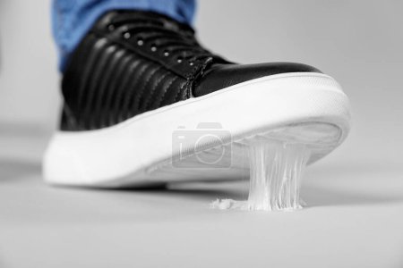 Man stepping into chewing gum on light grey background, closeup