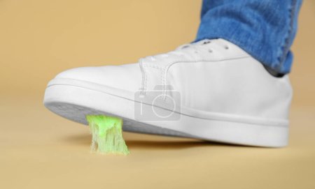 Person stepping into chewing gum on light brown background, closeup