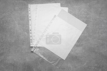 Photo for Punched pockets with paper sheets on grey table, flat lay. Space for text - Royalty Free Image