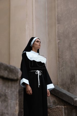 Téléchargez les photos : Beautiful young nun in cassock near building outdoors - en image libre de droit