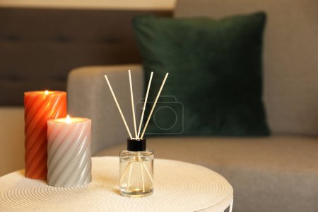 Foto de Aromatic reed air freshener and scented candles on table indoors, space for text - Imagen libre de derechos