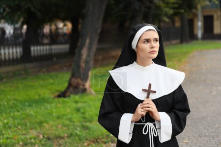 Téléchargez les photos : Young nun with Christian cross in park outdoors, space for text - en image libre de droit