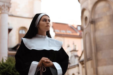 Téléchargez les photos : Beautiful young nun in cassock near building outdoors - en image libre de droit