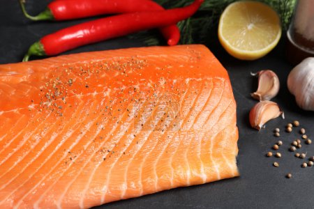 Téléchargez les photos : Saumon cru frais et ingrédients pour la marinade sur table noire, gros plan - en image libre de droit