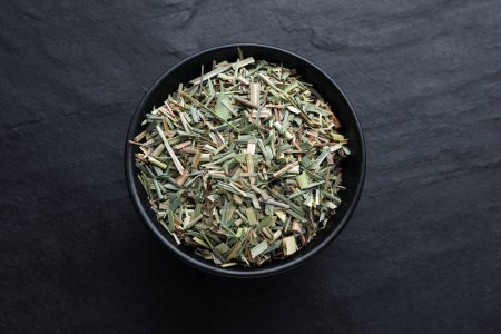 Téléchargez les photos : Bowl with aromatic dried lemongrass on black table, top view - en image libre de droit