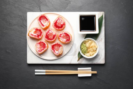 Foto de Delicious sushi rolls and chopsticks on black textured table, flat lay - Imagen libre de derechos
