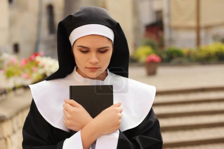 Téléchargez les photos : Young nun with Bible outdoors on city street - en image libre de droit