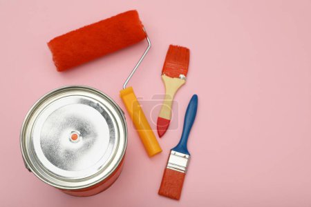 Téléchargez les photos : Bucket of orange paint, roller and brushes on pink background, flat lay. Space for text - en image libre de droit