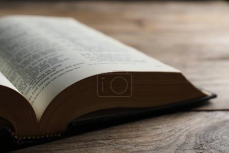 Open Bible on wooden table, closeup. Christian religious book