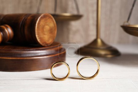 Divorce concept. Wedding rings on white wooden table, closeup with space for text