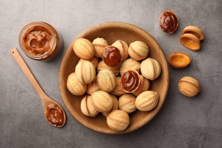 Téléchargez les photos : Delicious nut shaped cookies with boiled condensed milk on gray textured table, flat lay - en image libre de droit