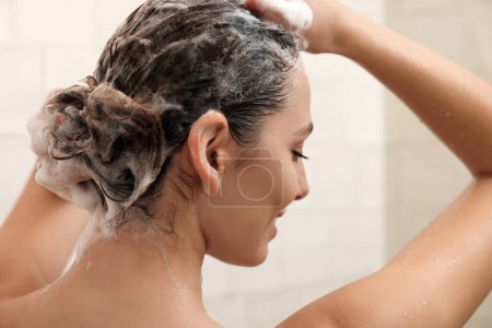 Téléchargez les photos : Jeune femme laver les cheveux tout en prenant une douche à la maison - en image libre de droit