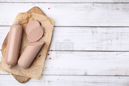 Board with delicious liver sausage on white wooden table, top view. Space for text