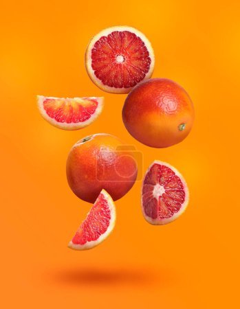 Photo for Many tasty Sicilian oranges falling on bright orange background - Royalty Free Image