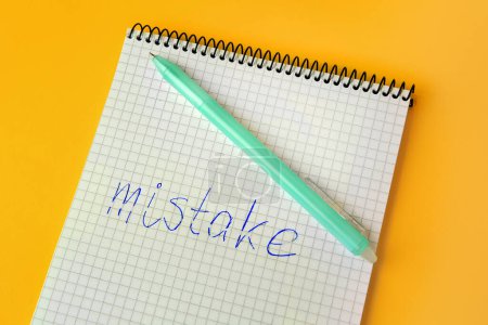 Photo for Word Mistake written with erasable pen in notepad on yellow background, above view - Royalty Free Image