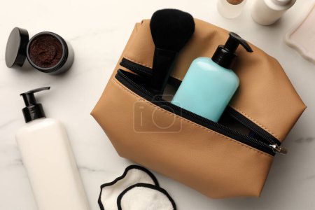 Photo for Preparation for spa. Compact toiletry bag and different cosmetic products on white marble table, flat lay - Royalty Free Image