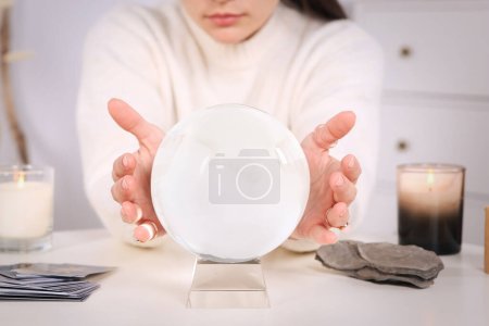 Photo for Soothsayer using crystal ball to predict future at table indoors, closeup - Royalty Free Image