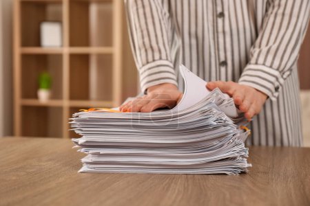 Woman stacking documents at wooden table indoors, closeup