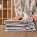 Woman stacking documents at wooden table indoors, closeup