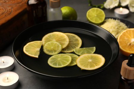 Foto de Cuenco de aceite esencial y limones sobre mesa gris. Tratamiento de aromaterapia - Imagen libre de derechos