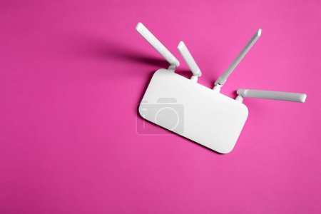 New white Wi-Fi router on pink background, top view. Space for text