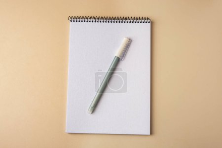 Photo for Notepad with erasable pen on beige background, top view - Royalty Free Image