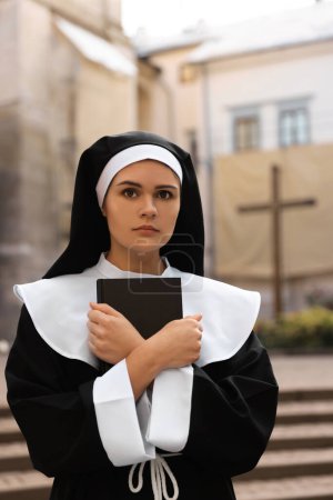 Téléchargez les photos : Young nun with Bible near building outdoors - en image libre de droit