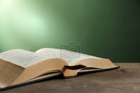 Foto de Open Bible on wooden table against green background. Space for text - Imagen libre de derechos