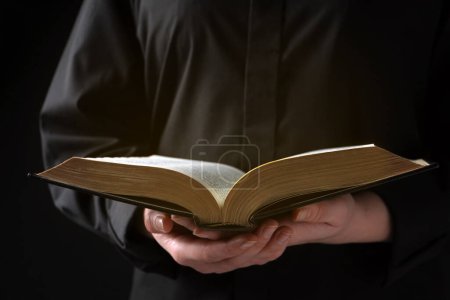 Téléchargez les photos : Woman reading holy Bible on black background, closeup - en image libre de droit
