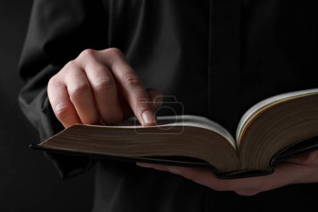 Téléchargez les photos : Woman reading holy Bible on black background, closeup - en image libre de droit