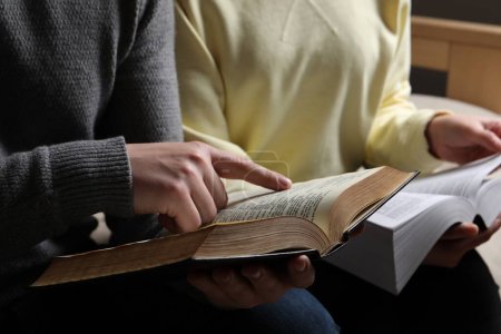 Couple reading Bibles in room, closeup view