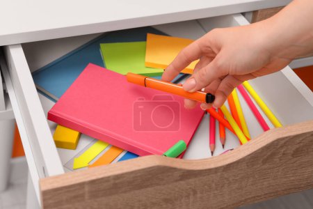 Téléchargez les photos : Woman putting marker into desk drawer, closeup - en image libre de droit