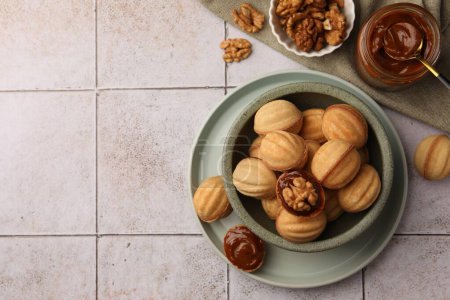 Téléchargez les photos : Delicious nut shaped cookies with boiled condensed milk on light textured table, flat lay. Space for text - en image libre de droit