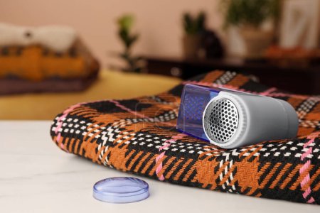 Photo for Modern fabric shaver and cloth on white table indoors, closeup. Space for text - Royalty Free Image