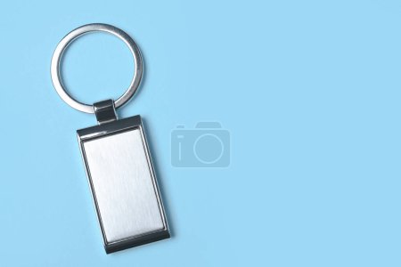 Metallic keychain on light blue background, top view. Space for text