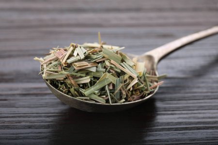 Téléchargez les photos : Metal spoon with aromatic dried lemongrass on wooden table, closeup - en image libre de droit
