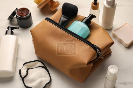 Photo for Preparation for spa. Compact toiletry bag and different cosmetic products on white marble table - Royalty Free Image