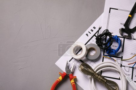 Foto de Diferentes alambres, herramientas de electricista y esquemas en mesa gris, planas. Espacio para texto - Imagen libre de derechos