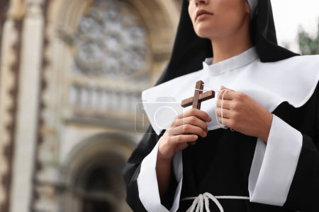Téléchargez les photos : Jeune religieuse avec croix chrétienne près de la cathédrale à l'extérieur, gros plan. Espace pour le texte - en image libre de droit
