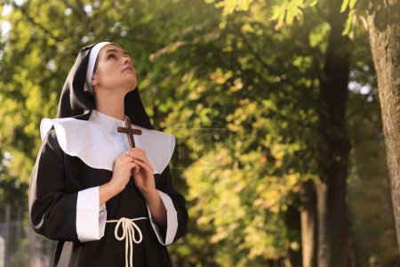 Téléchargez les photos : Jeune religieuse avec croix chrétienne dans le parc le jour ensoleillé, espace pour le texte - en image libre de droit