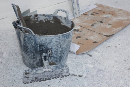 Photo for Bucket with cement and putty knifes indoors. Home improvement - Royalty Free Image