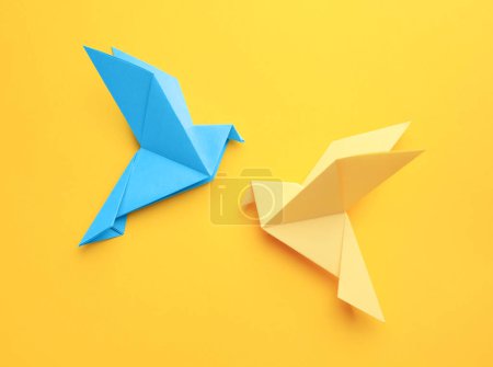 Foto de Origami art. Colorful handmade paper birds on yellow background, flat lay - Imagen libre de derechos