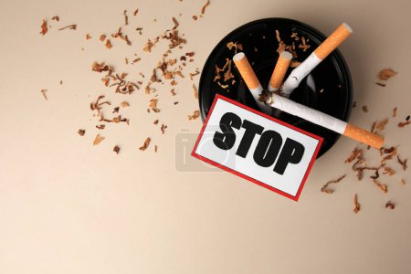 Photo for Card with word Stop, ashtray and cigarette stubs on beige background, flat lay with space for text. Quitting smoking concept - Royalty Free Image