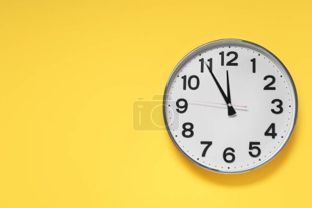 Photo for Clock showing five minutes until midnight on yellow background, top view with space for text. New Year countdown - Royalty Free Image
