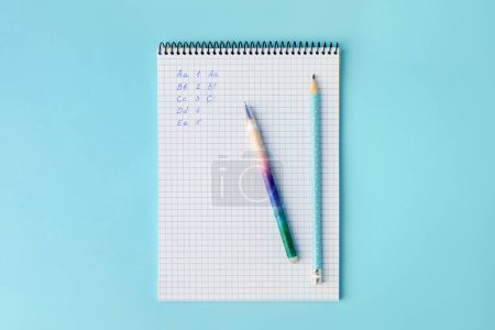 Photo for Letters and numbers written in notepad with erasable pens on light blue background, top view - Royalty Free Image