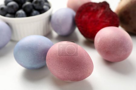 Colorful Easter eggs painted with natural dyes on white table, closeup